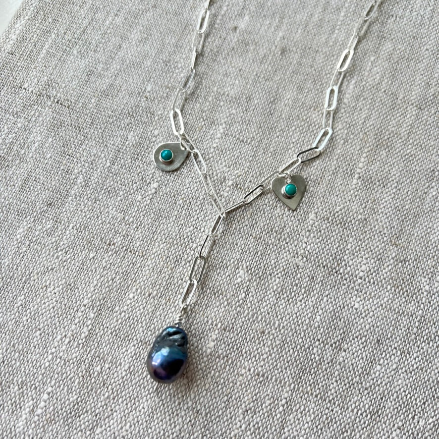 Handmade sterling silver charm necklace with beautiful blue gray baroque pearl in the center, flanked by sterling silver heart and sterling silver teardrop with blue turquoise. This one of a kind charm necklace looks stunning on.