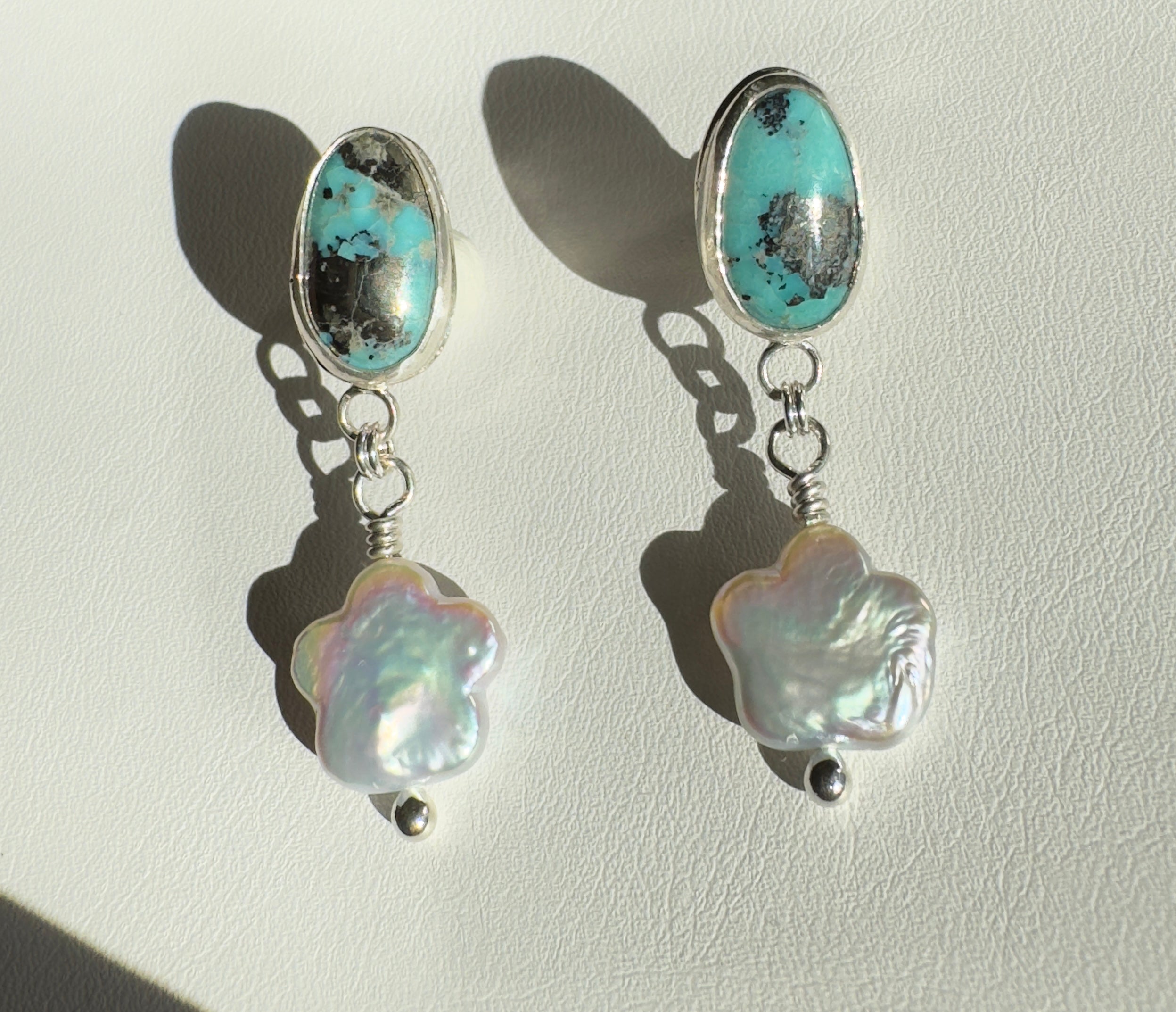 Robin's Egg Blue Kingman Turquoise set in a fine silver bezel with flower shaped pearls dangling below. The posts and ear backs are sterling silver. 