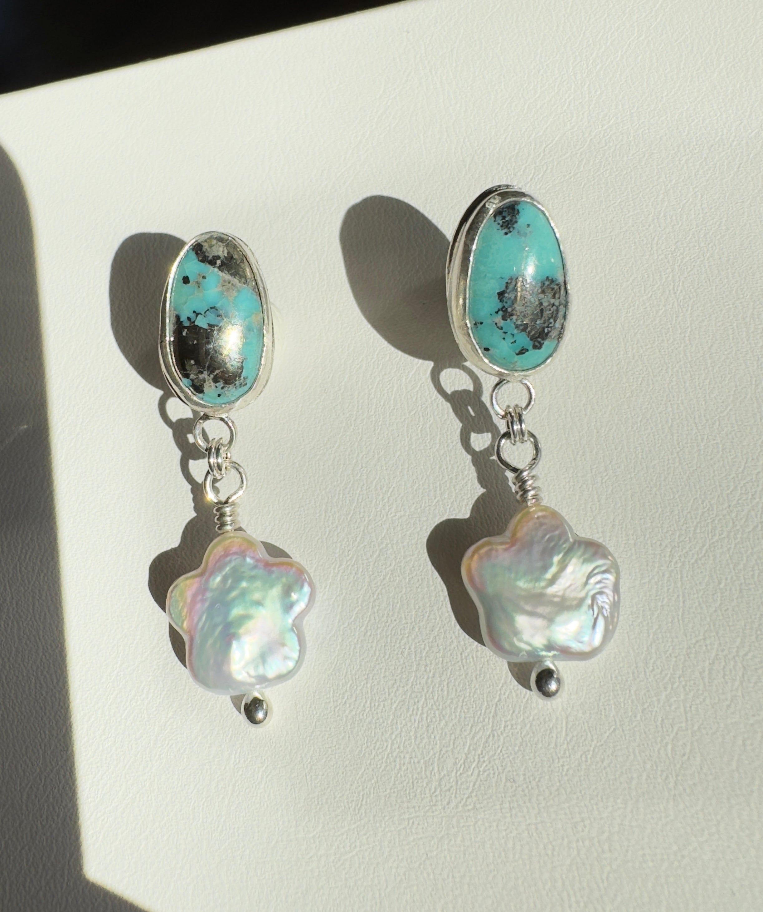 Robin's Egg Blue Kingman Turquoise set in a fine silver bezel with flower shaped pearls dangling below. The posts and ear backs are sterling silver. 