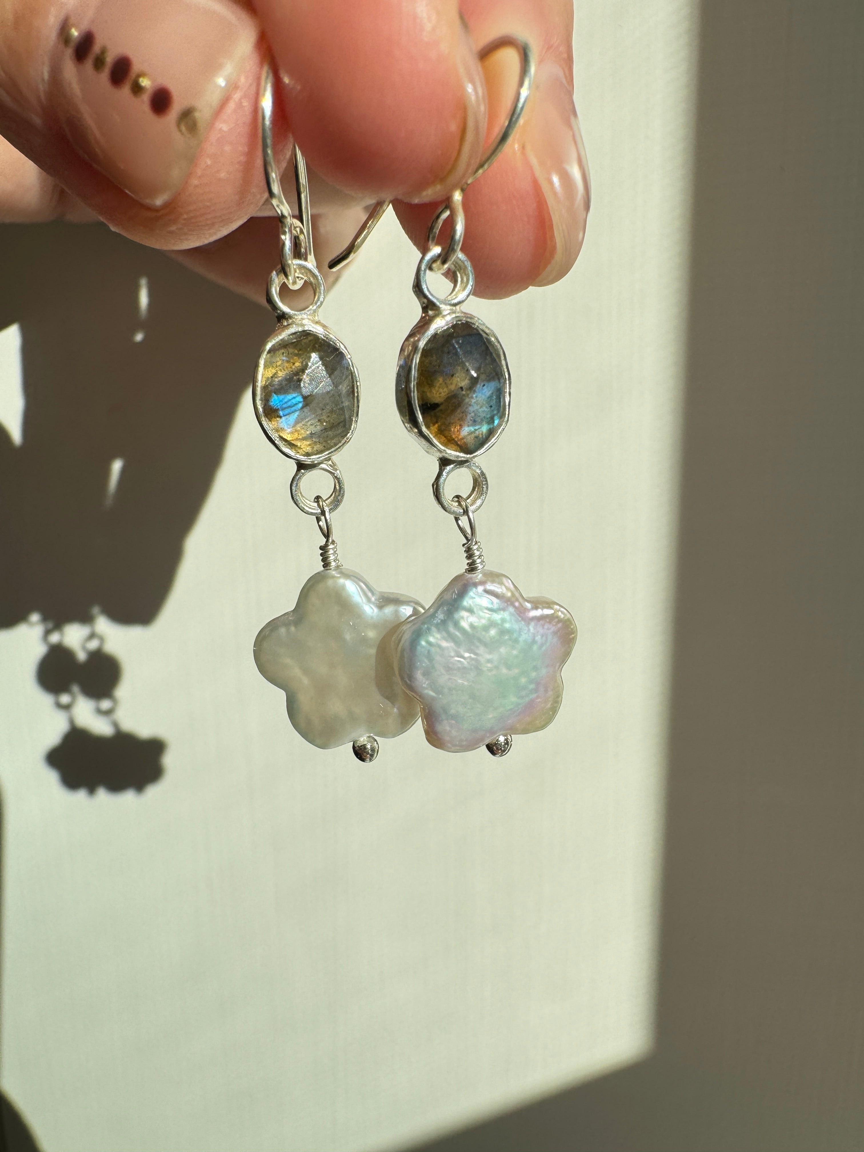 Icy blue labradorite set in a fine silver bezel on a sterling silver back with freshwater flower-shaped pearls dangling below.