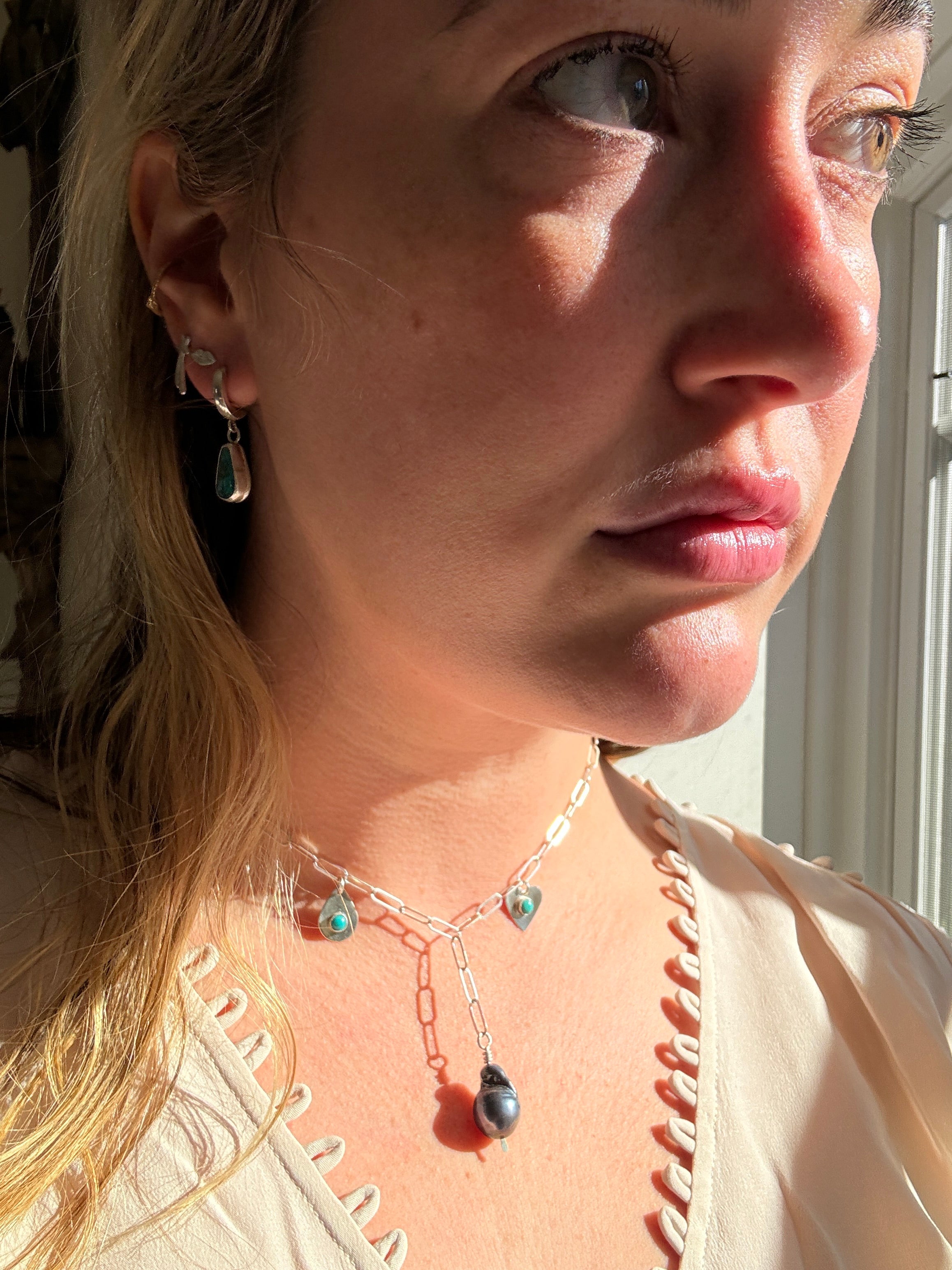 Handmade sterling silver charm necklace with beautiful blue gray baroque pearl in the center, flanked by sterling silver heart and sterling silver teardrop with blue turquoise. This one of a kind charm necklace looks stunning on.