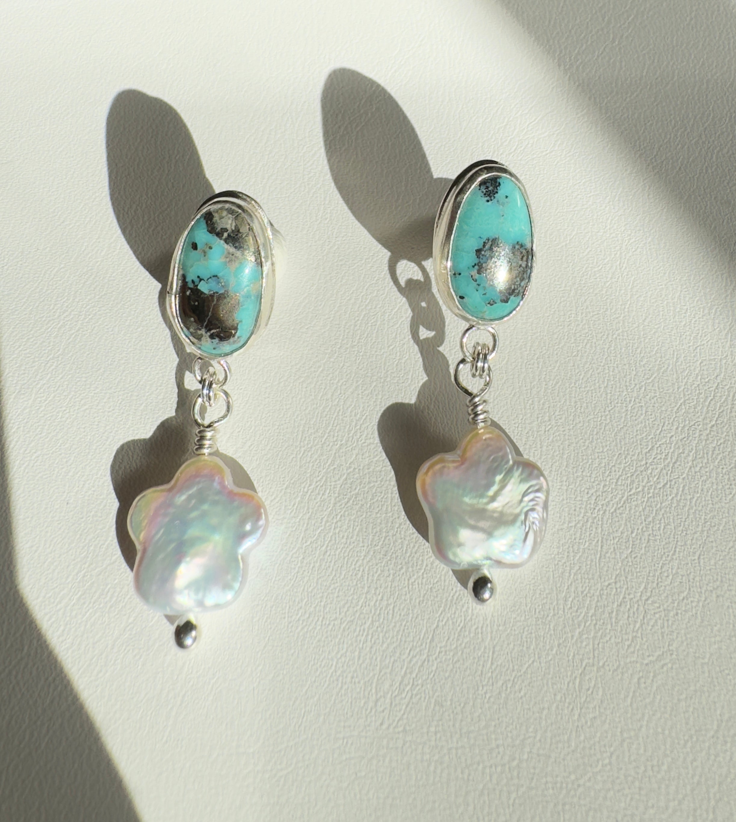 Robin's Egg Blue Kingman Turquoise set in a fine silver bezel with flower shaped pearls dangling below. The posts and ear backs are sterling silver. 