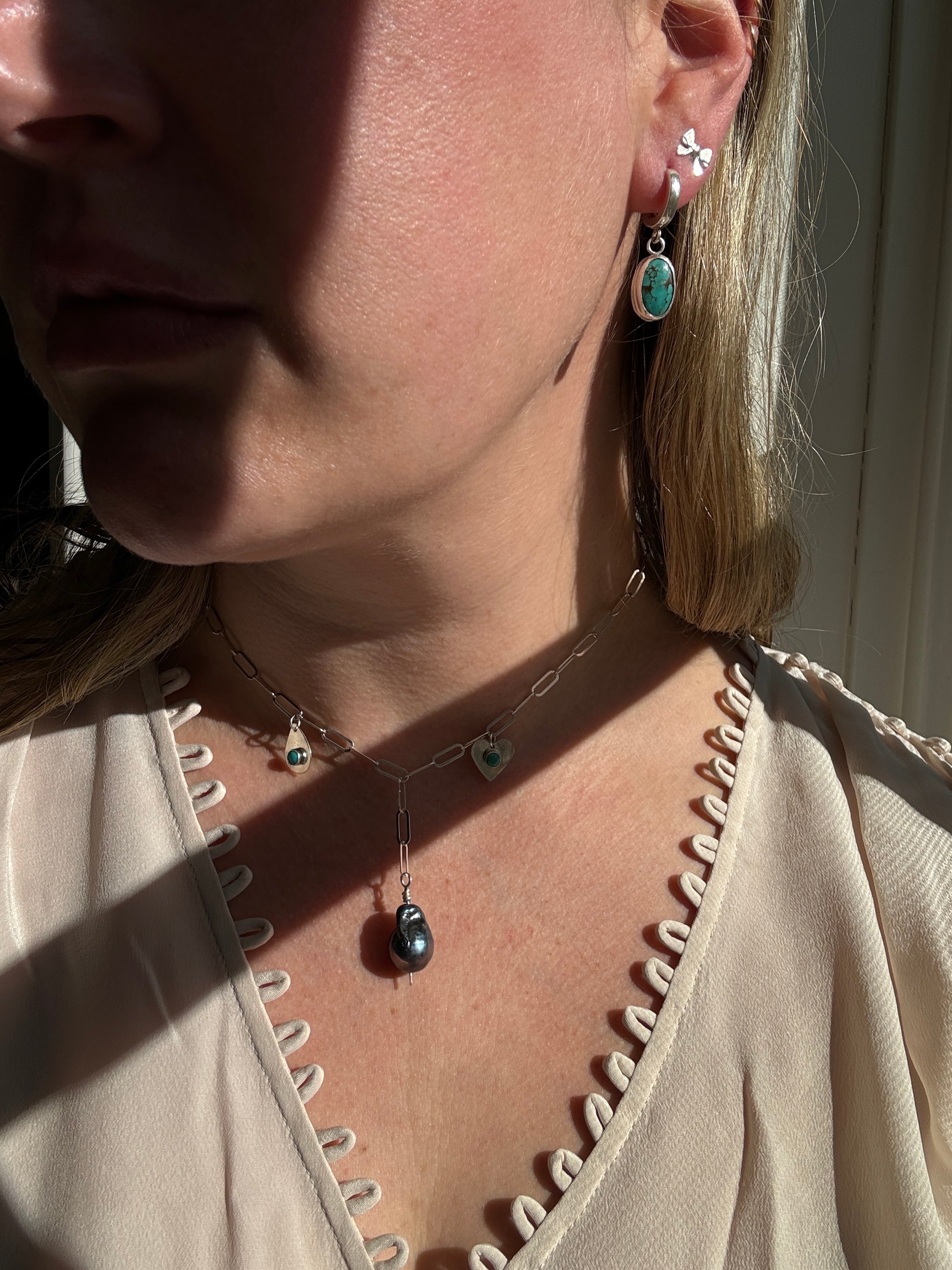 Handmade sterling silver charm necklace with beautiful blue gray baroque pearl in the center, flanked by sterling silver heart and sterling silver teardrop with blue turquoise. This one of a kind charm necklace looks stunning on.