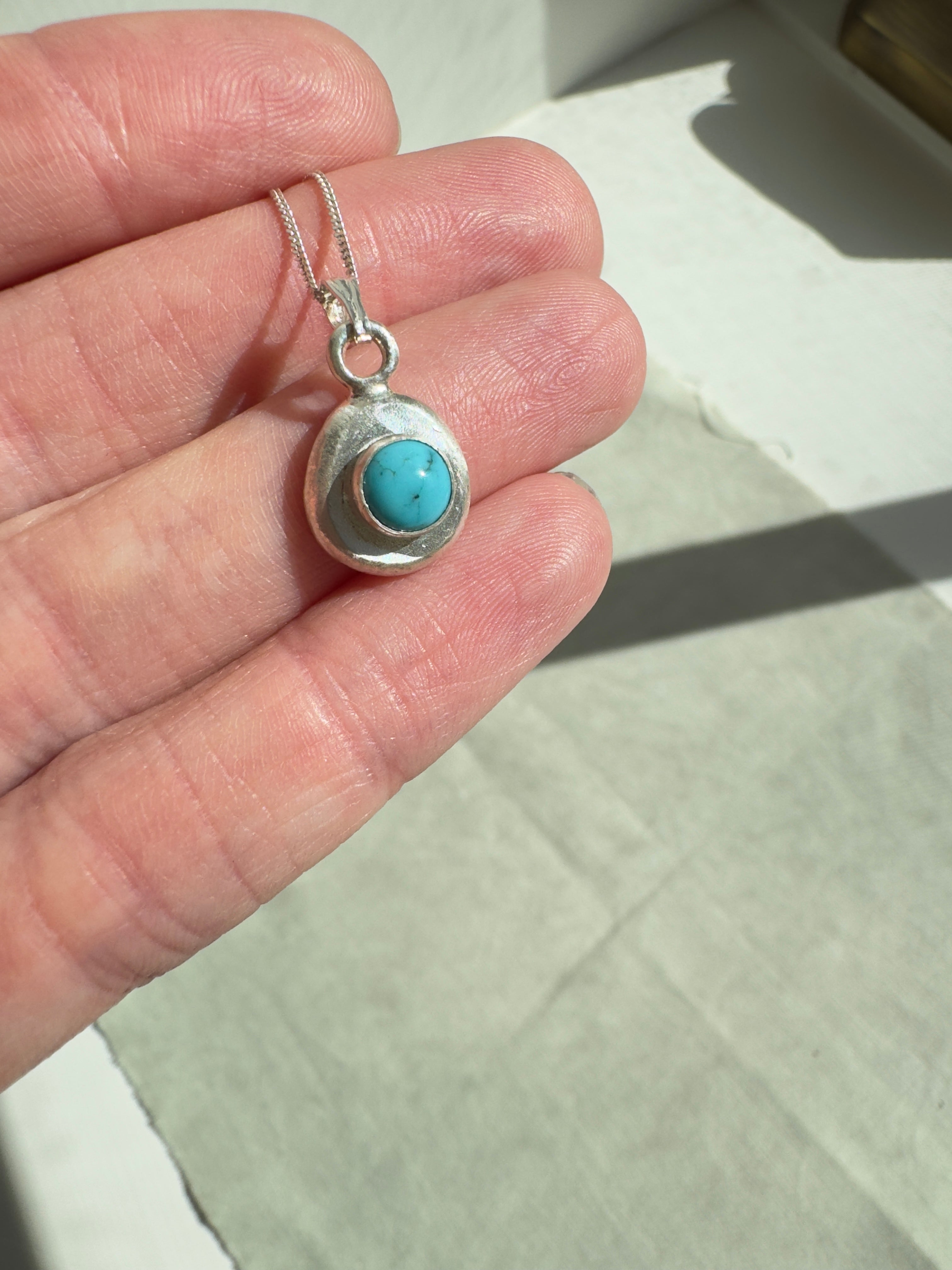 6mm Sonora Turquoise on a hand forged nugget of sterling silver. Choose between a 16” or 18” sterling silver diamond cut curb chain. Each necklace will vary slightly as they are all unique.