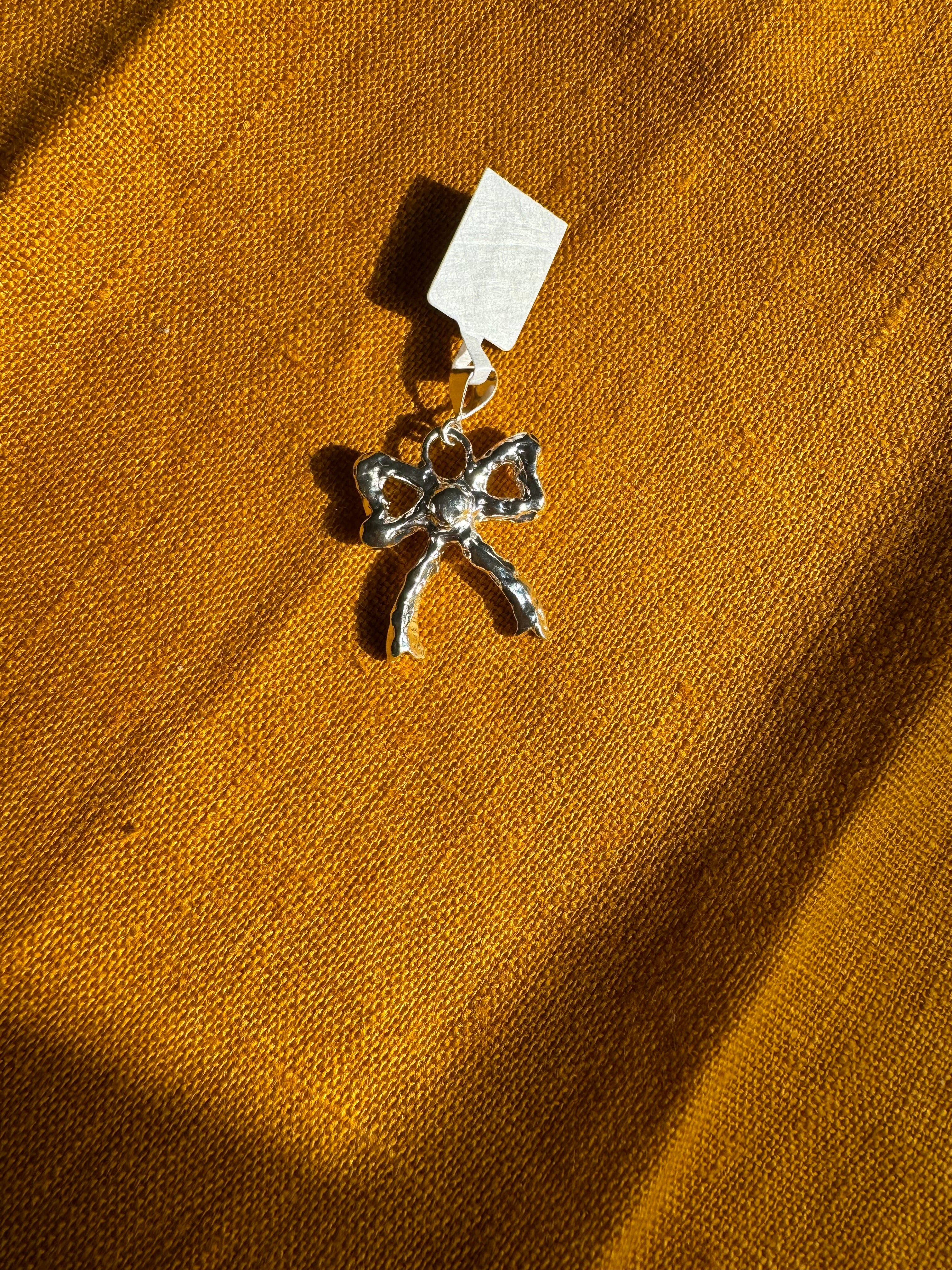 sterling silver bow charm on a yellow fabric background