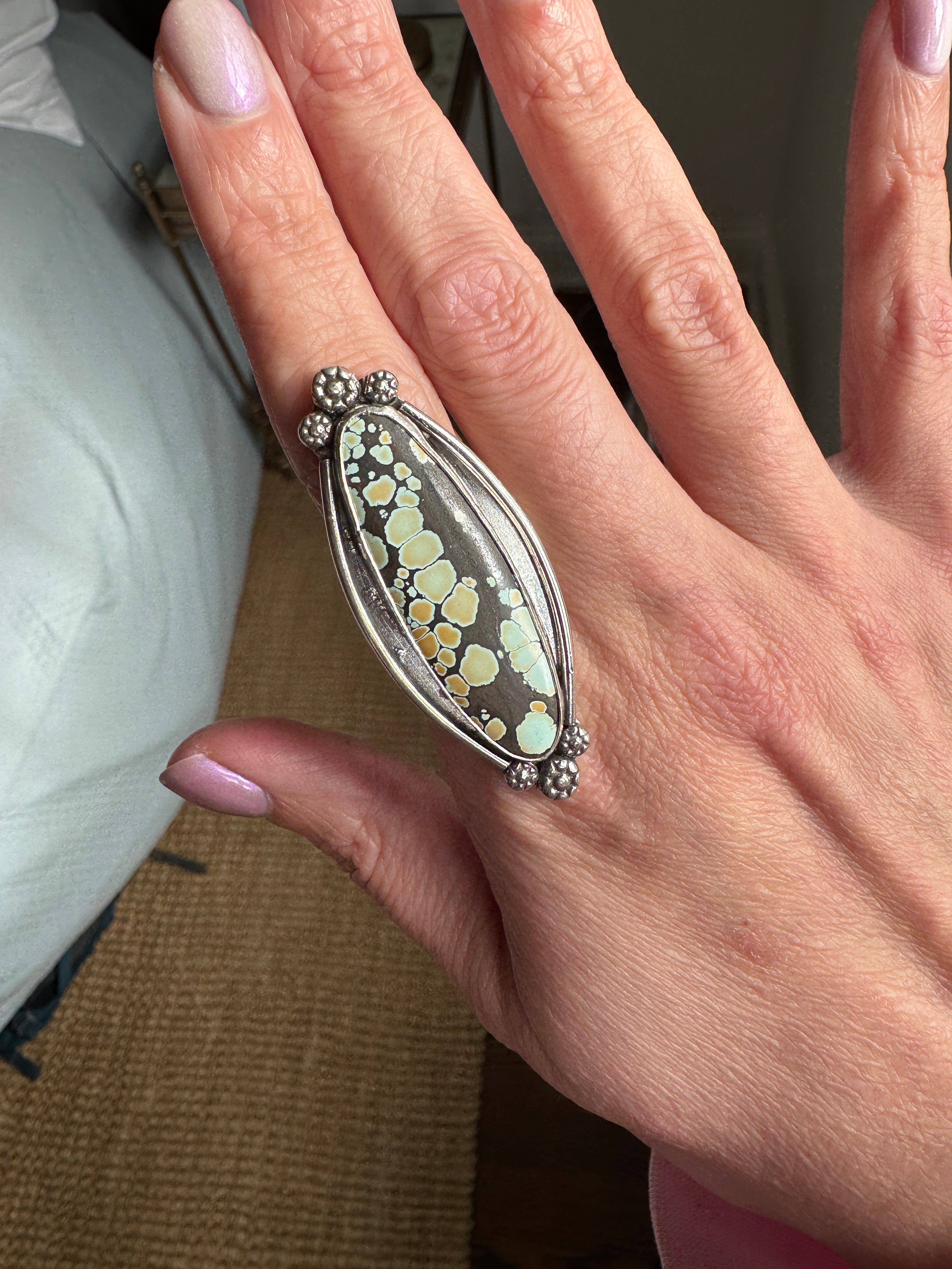 Close-up of a hand wearing a decorative ring with turquoise.