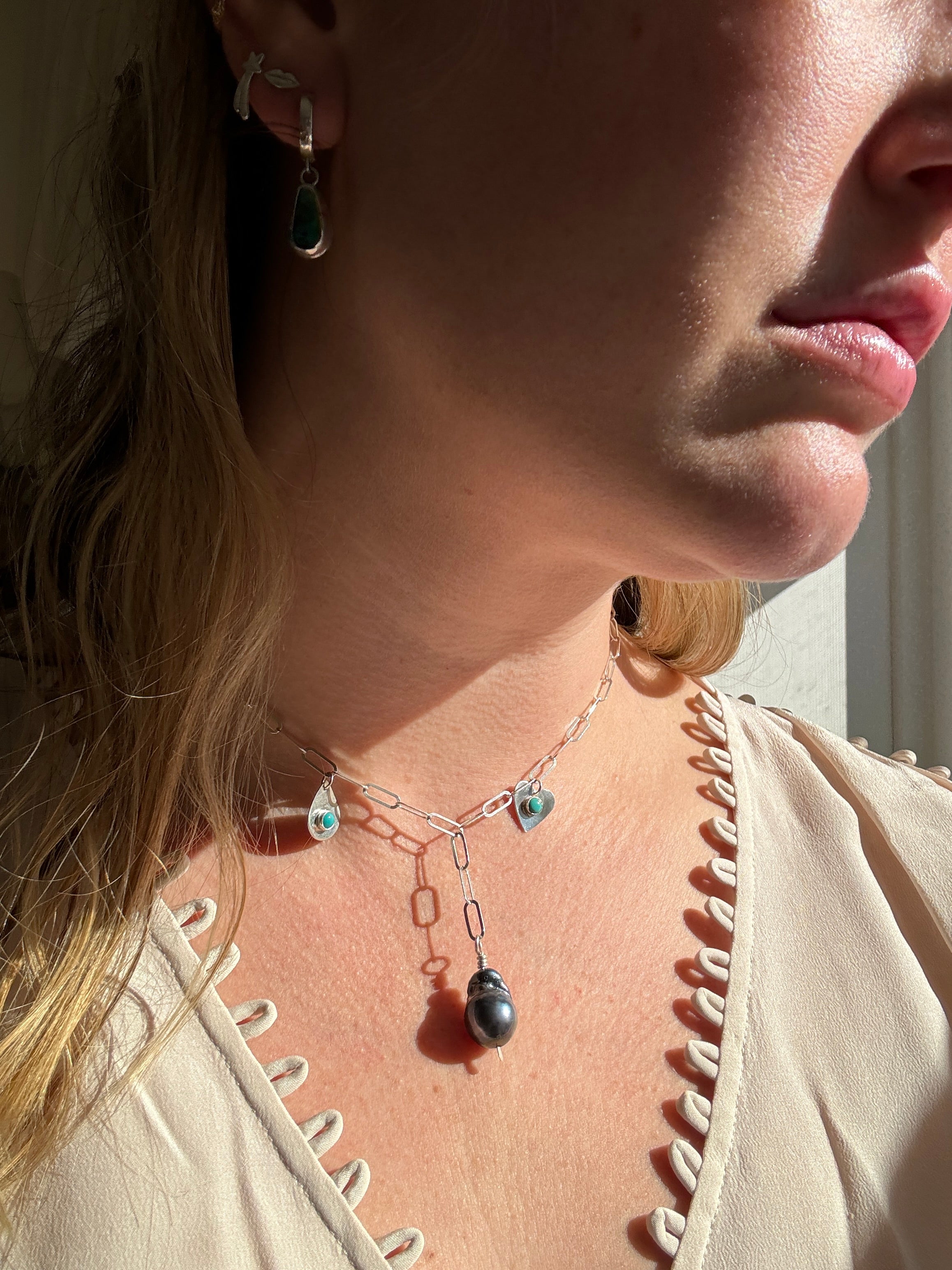 Handmade sterling silver charm necklace with beautiful blue gray baroque pearl in the center, flanked by sterling silver heart and sterling silver teardrop with blue turquoise. This one of a kind charm necklace looks stunning on.