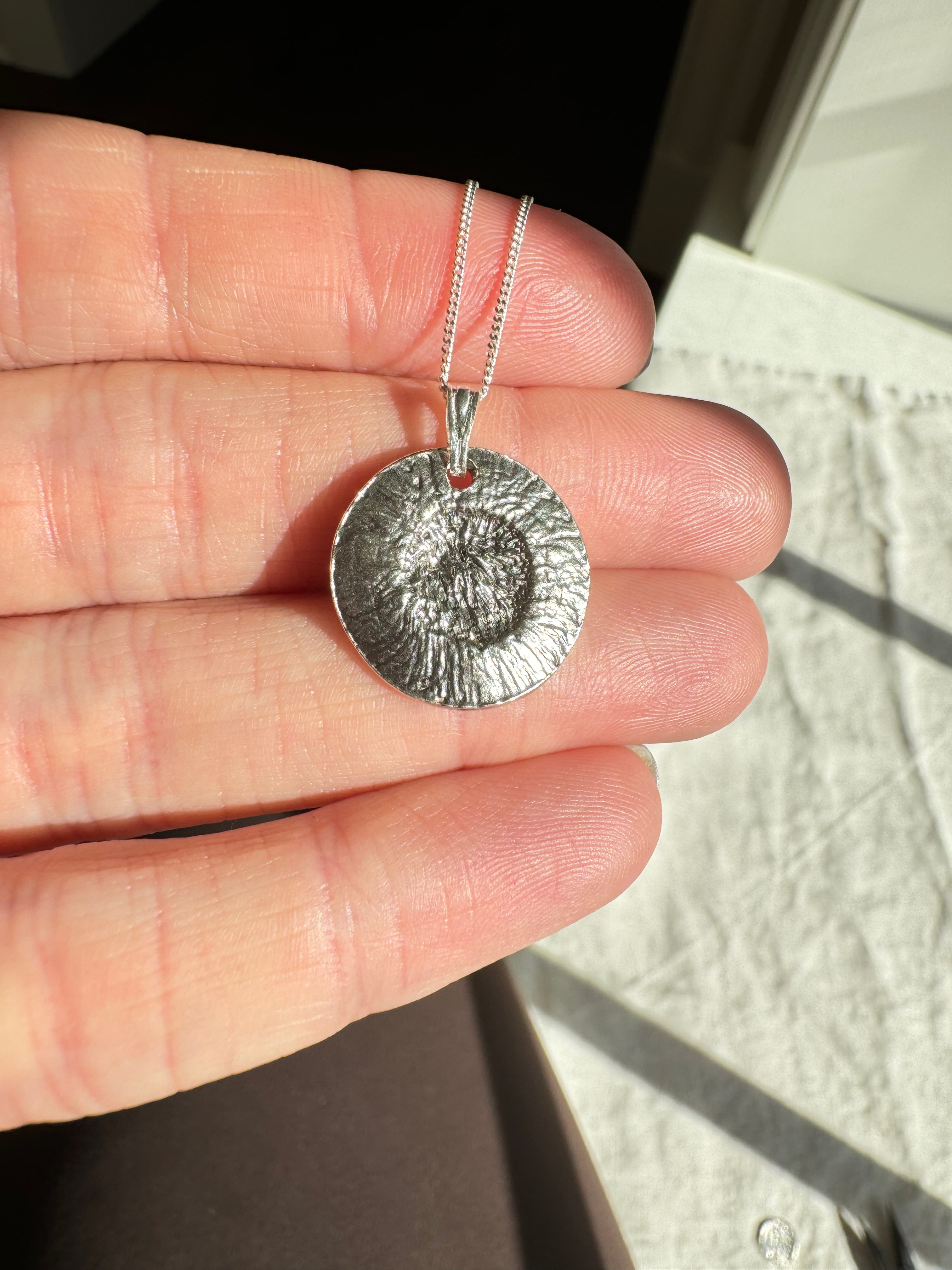Hand pressed aster on fine silver with a sterling silver bail. Choose between a 16” or 18” sterling silver diamond cut curb chain.