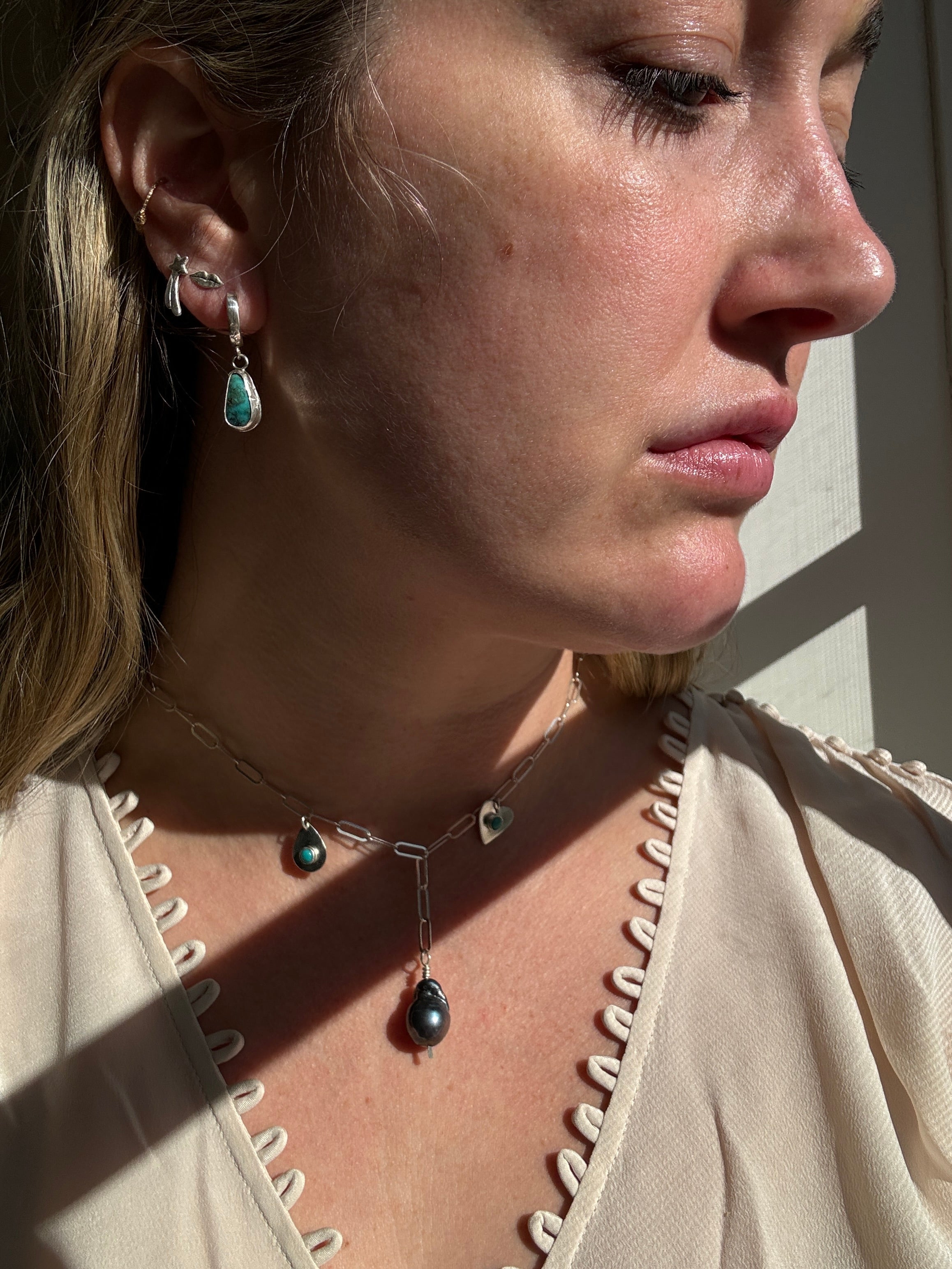 Handmade sterling silver charm necklace with beautiful blue gray baroque pearl in the center, flanked by sterling silver heart and sterling silver teardrop with blue turquoise. This one of a kind charm necklace looks stunning on. 