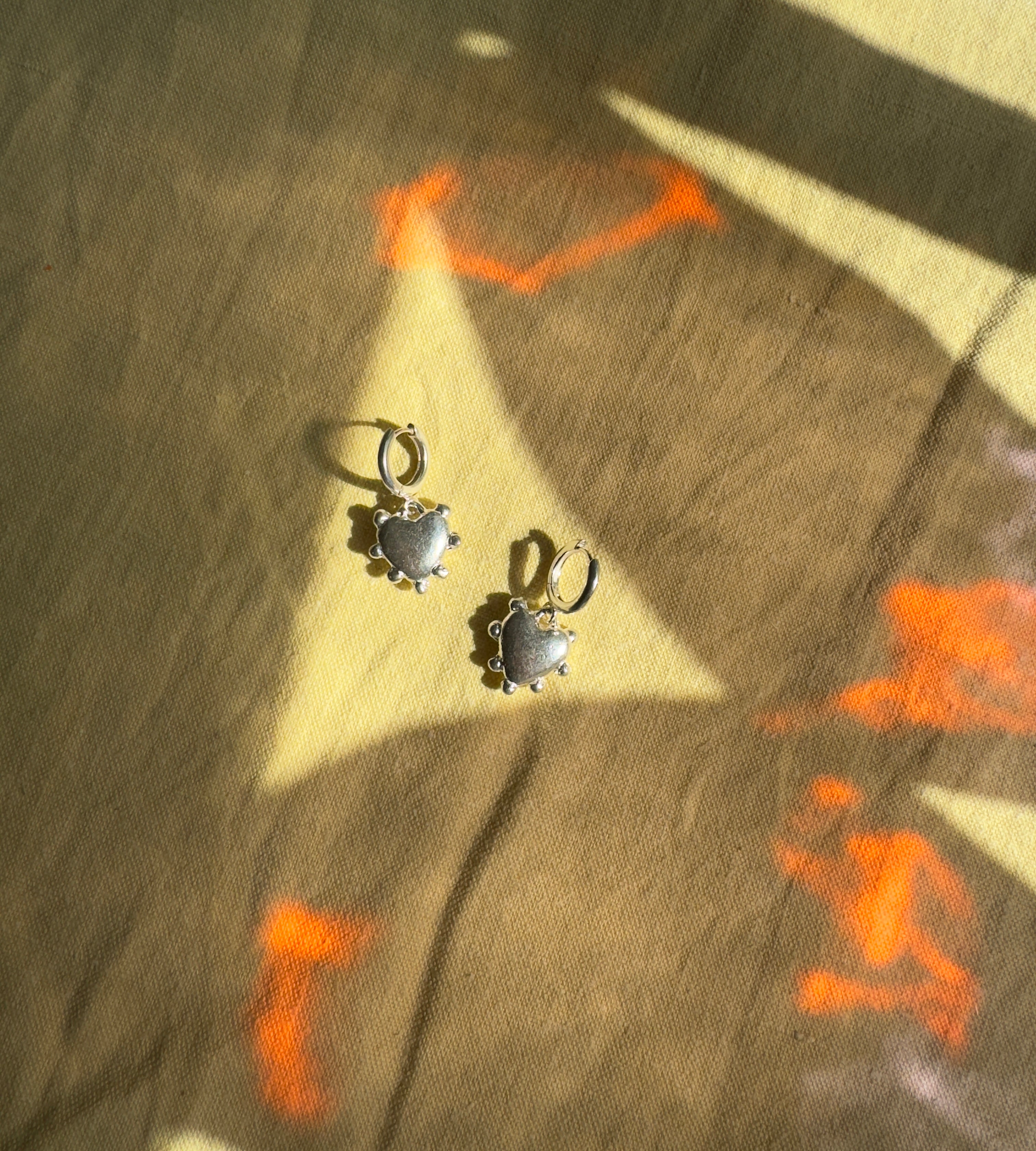 Thick sterling silver hearts bordered with dots. These are castings from an original mold that I created out of wax. These are solid silver but still light enough to wear as everyday earrings. The hoops are sterling silver as well.