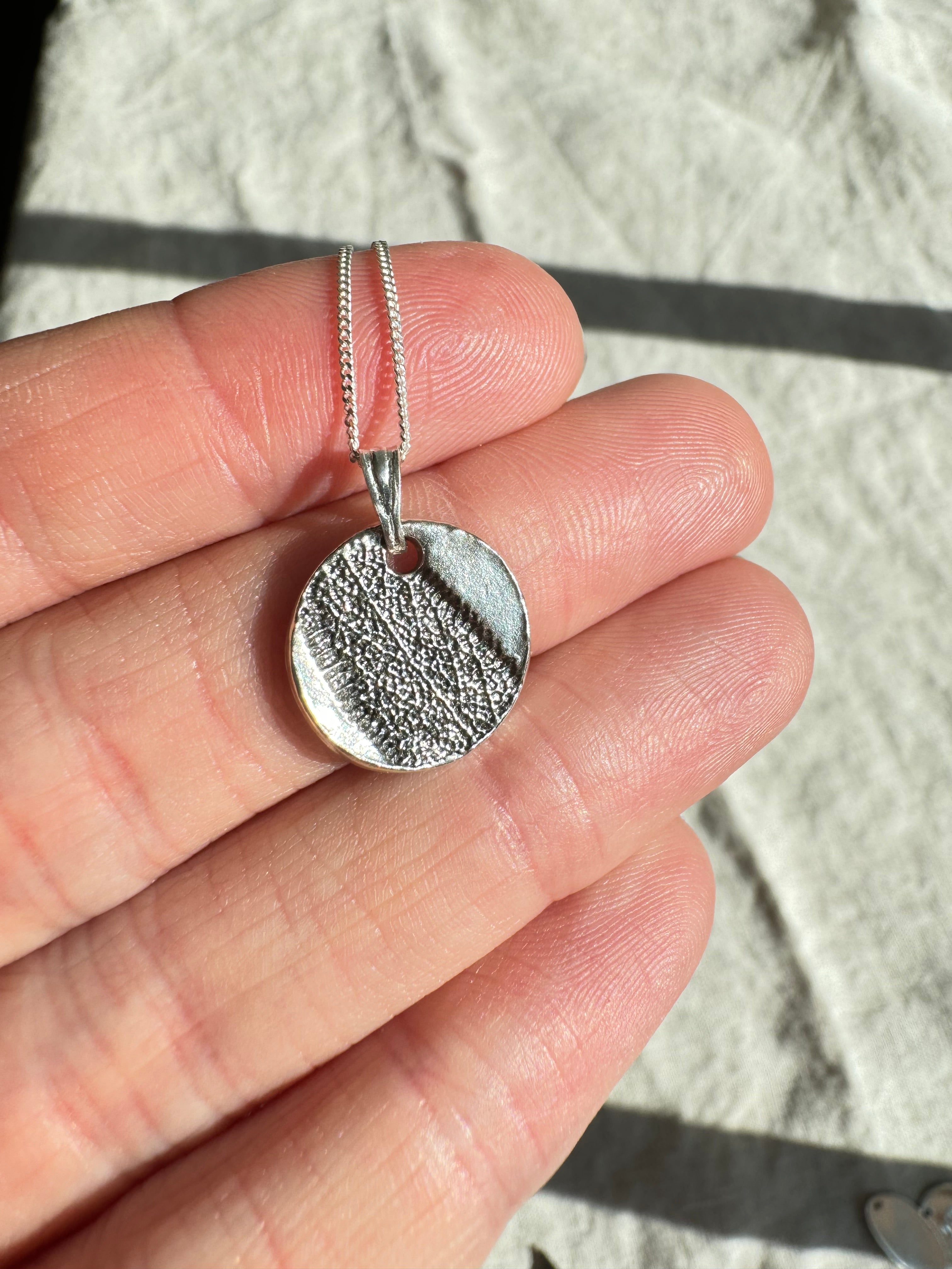 Hand pressed aster on fine silver with a sterling silver bail. Choose between a 16” or 18” sterling silver diamond cut curb chain.