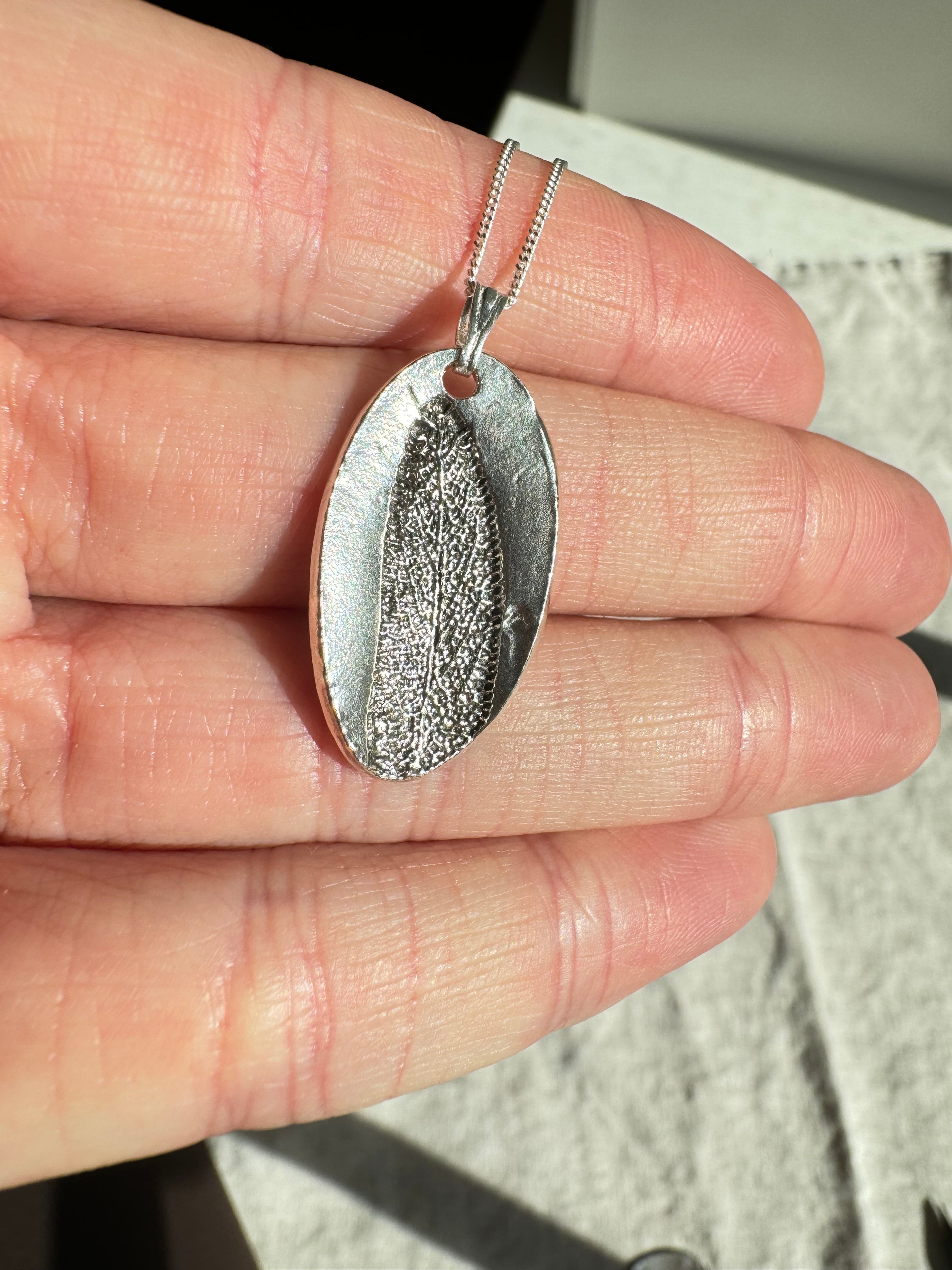 Hand pressed sage on fine silver with a sterling silver chain.