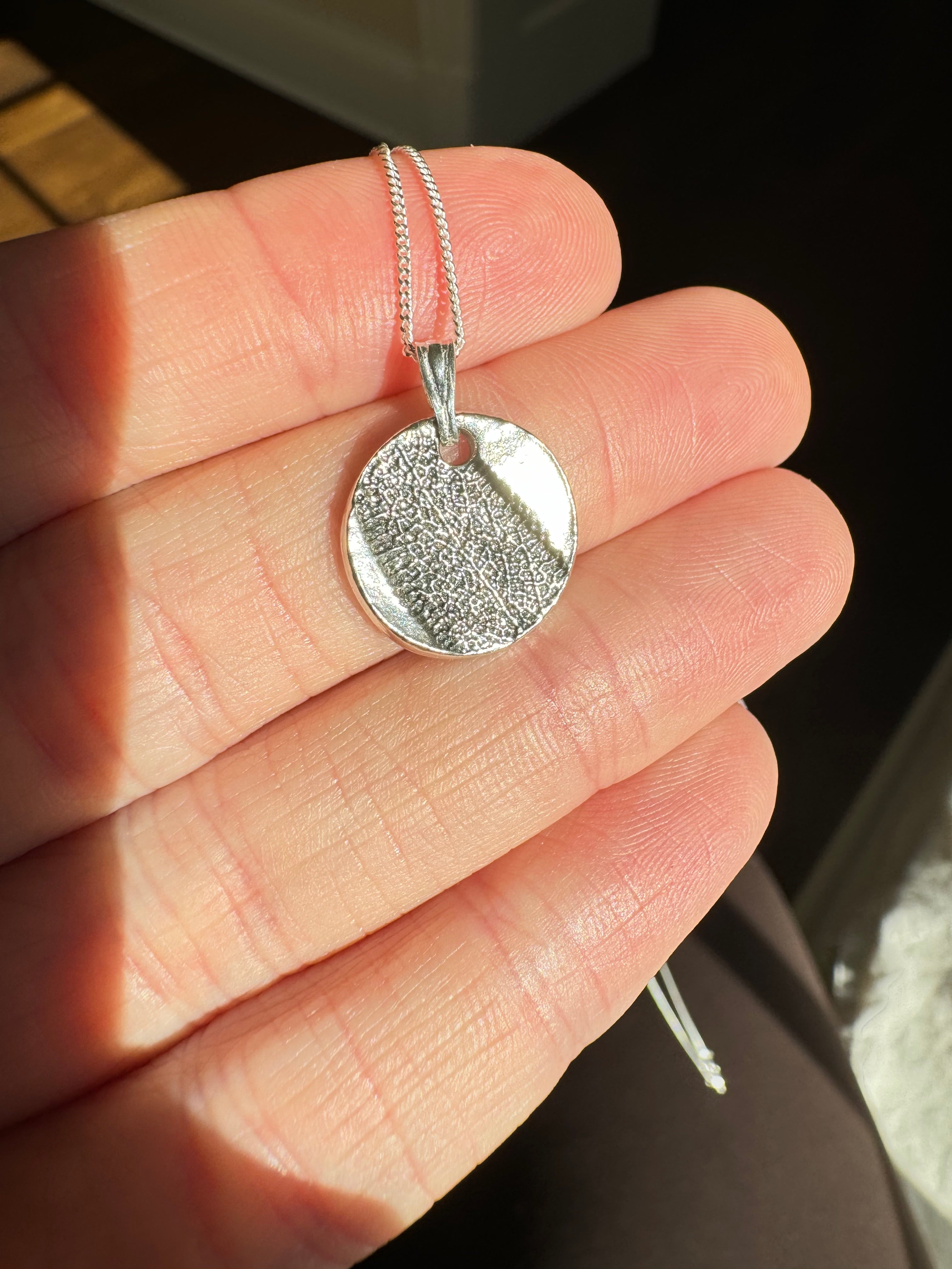 Hand pressed aster on fine silver with a sterling silver bail. Choose between a 16” or 18” sterling silver diamond cut curb chain.