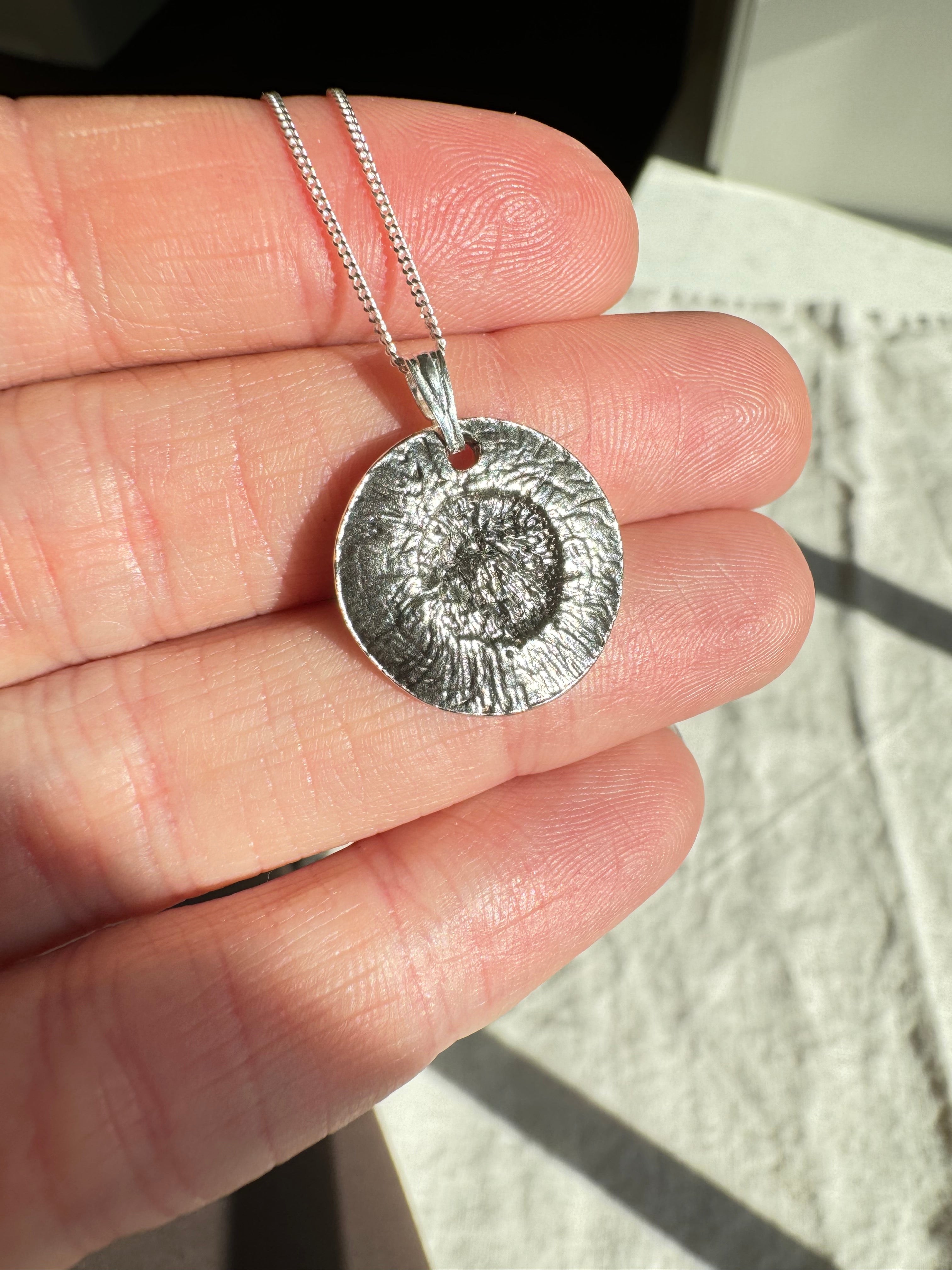 Hand pressed aster on fine silver with a sterling silver bail. Choose between a 16” or 18” sterling silver diamond cut curb chain.
