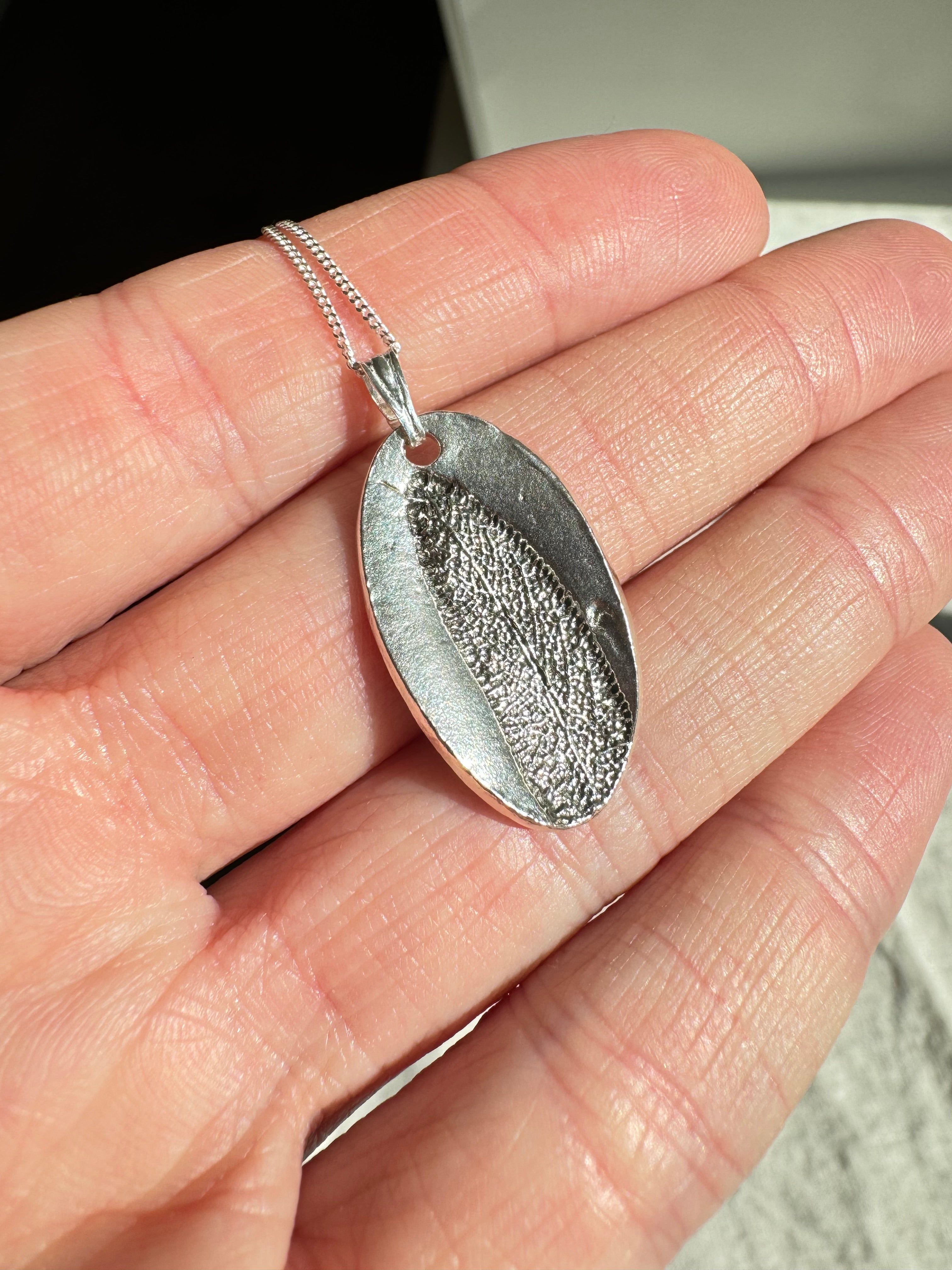 Hand pressed sage on fine silver with a sterling silver chain.