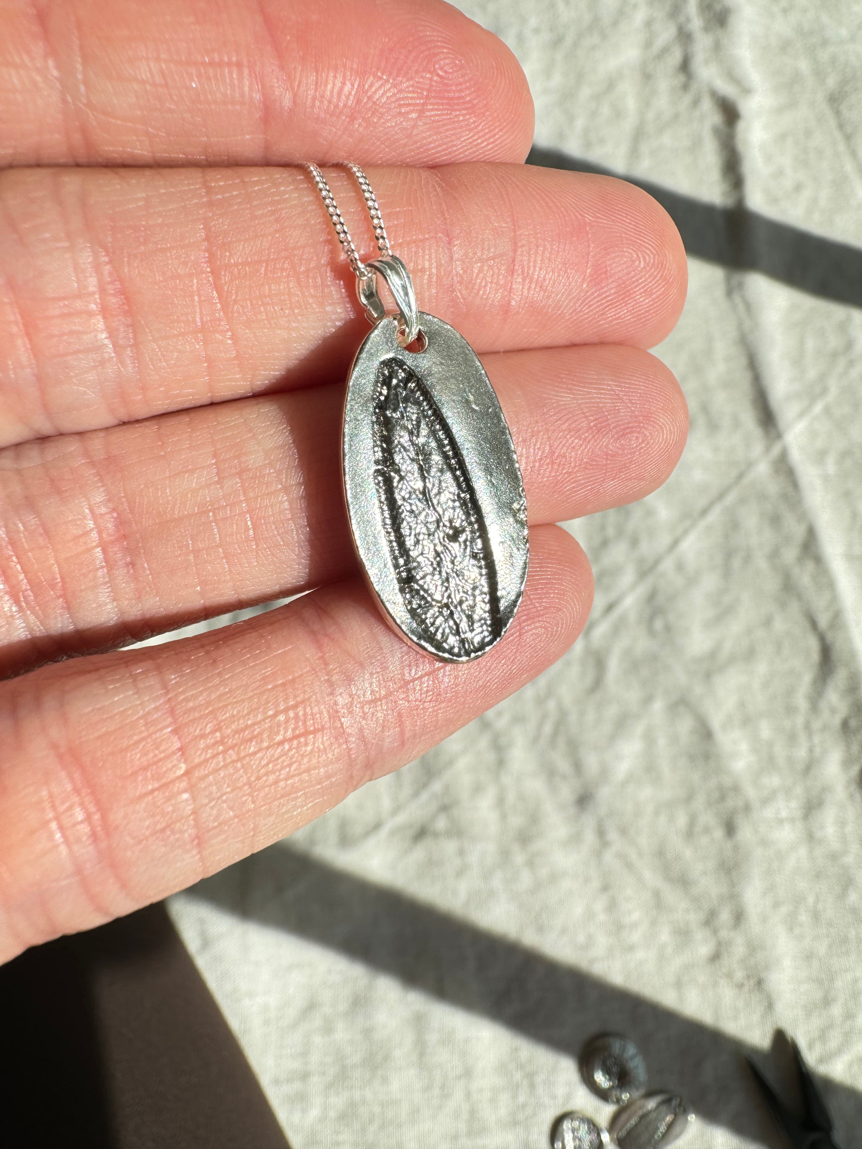 Hand pressed sage on fine silver with a sterling silver bail. Choose between a 16” or 18” sterling silver diamond cut curb chain.