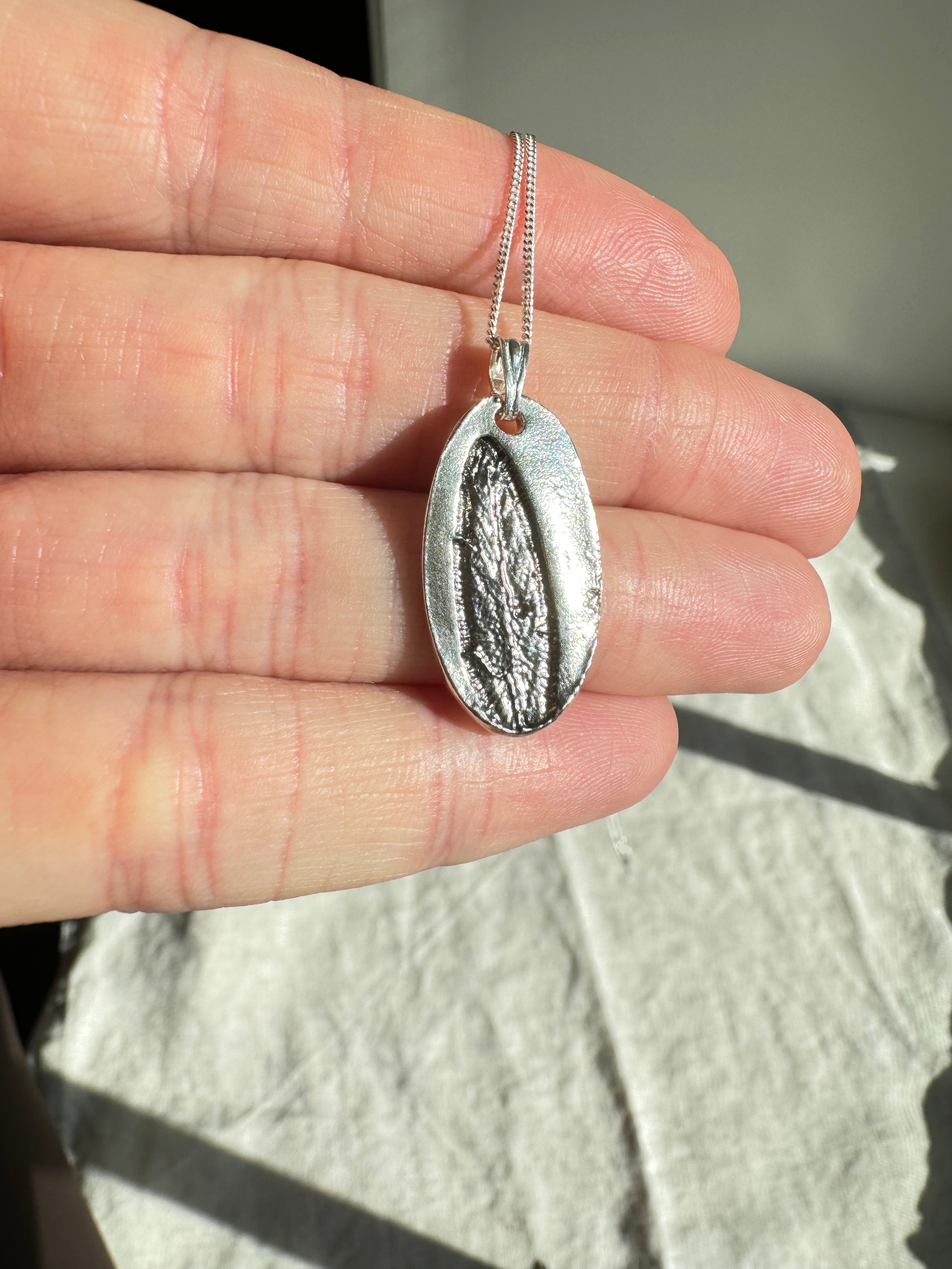 Hand pressed sage on fine silver with a sterling silver bail. Choose between a 16” or 18” sterling silver diamond cut curb chain.